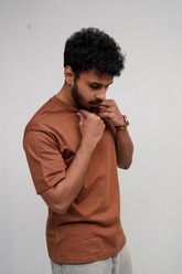 Man wearing a brown t-shirt against a plain background