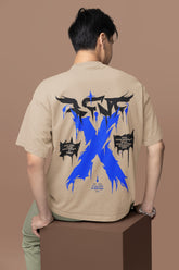 Person wearing a beige t-shirt with a blue 'X' design on the back against a brown background