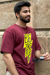 Man wearing a beige t-shirt with a graphic and text on a yellow background