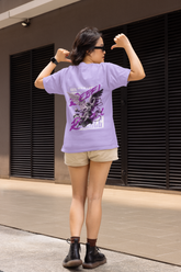 Person wearing a purple t-shirt with a graphic design, flexing their muscles outdoors.