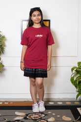 Person wearing a red 'LABURU' t-shirt and black skirt standing indoors.