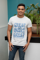 Man wearing a white t-shirt with blue text and graphics, standing indoors with plants in the background.