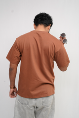 Person wearing a brown t-shirt and gray pants against a white background