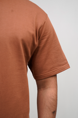 Brown t-shirt worn by a person on a light gray background