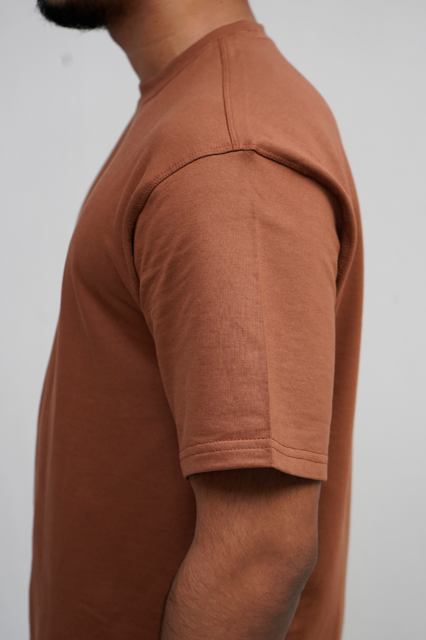 Person wearing a brown t-shirt against a plain background