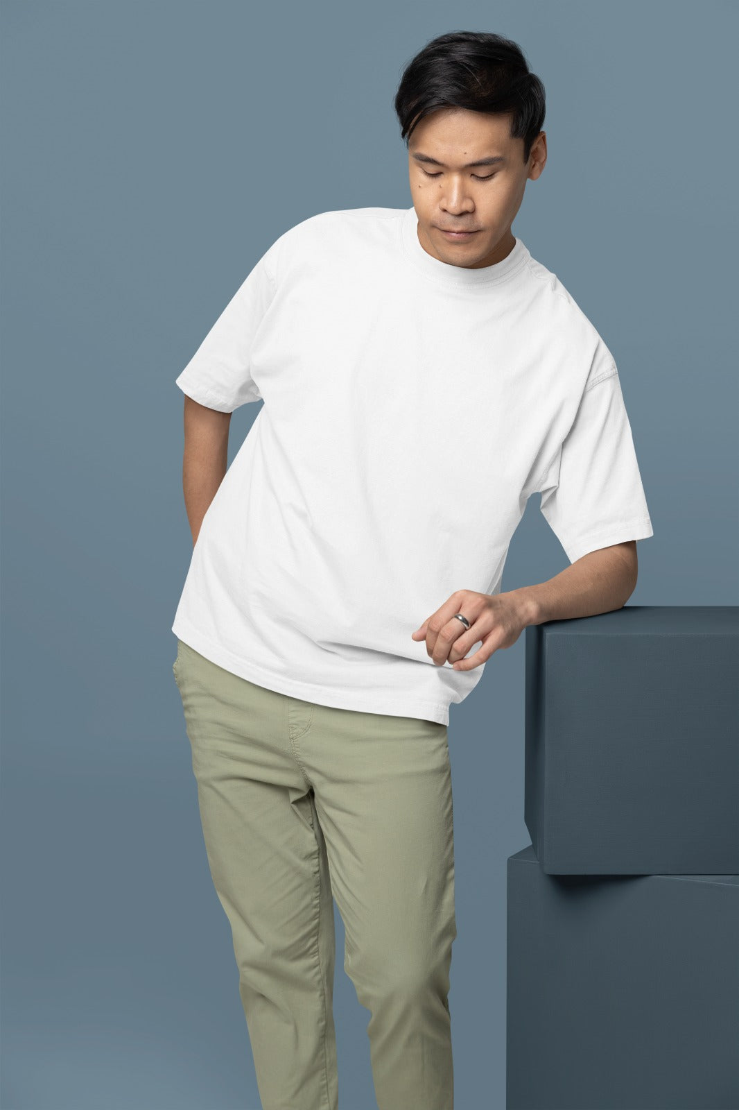 Man wearing a white t-shirt and beige pants against a gray background