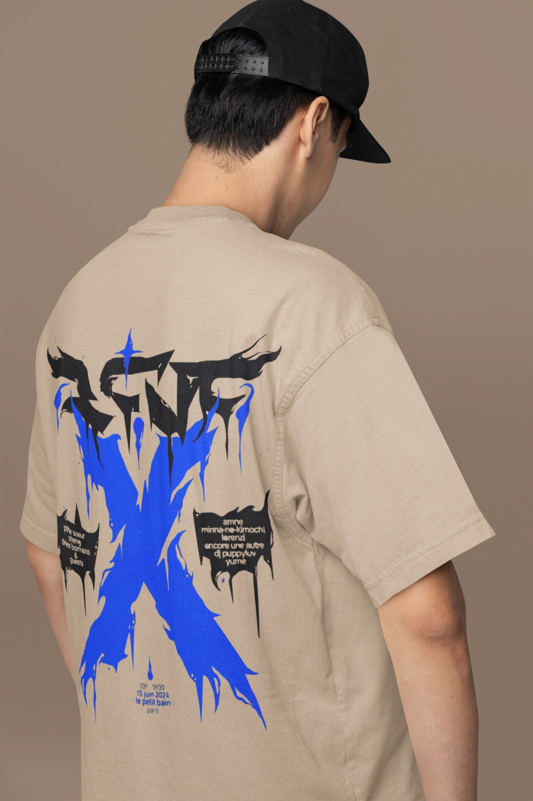 Person wearing a beige t-shirt with a blue and black graphic design on the back against a brown background