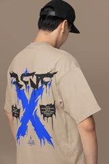 Person wearing a beige t-shirt with a blue and black graphic design on the back against a brown background