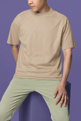 Person wearing a beige t-shirt and light green pants on a purple background