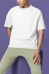Person wearing a white t-shirt and light green pants against a purple background