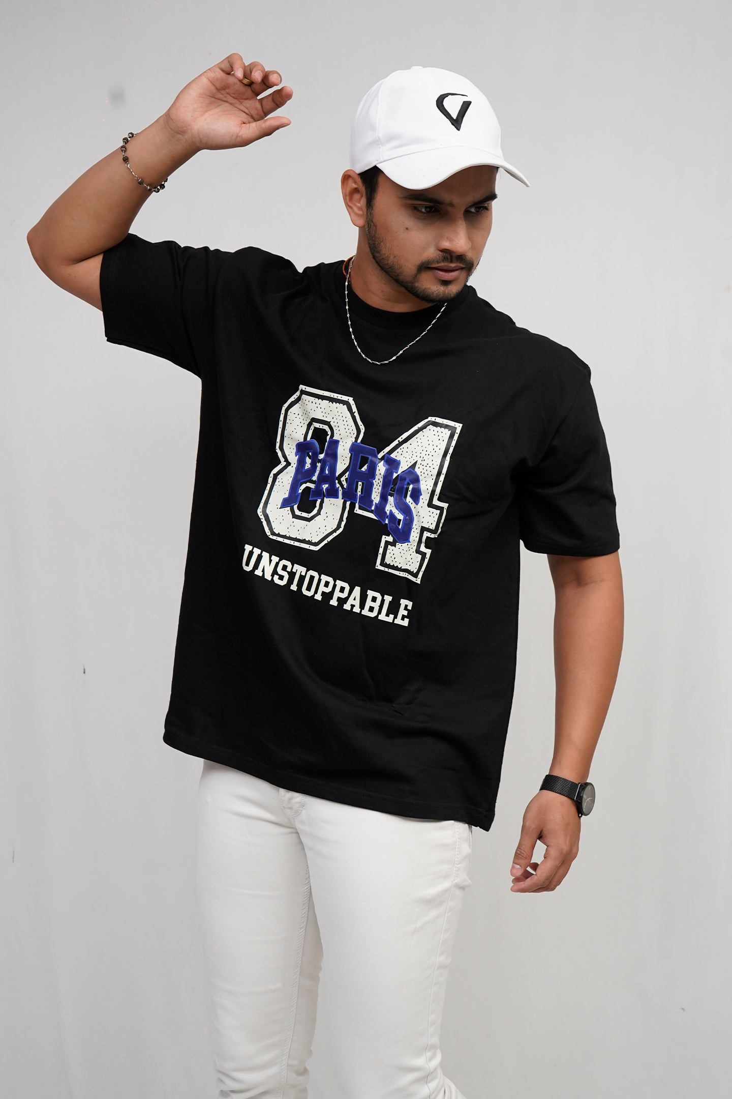 Person wearing a black t-shirt with text and a white cap on a plain background