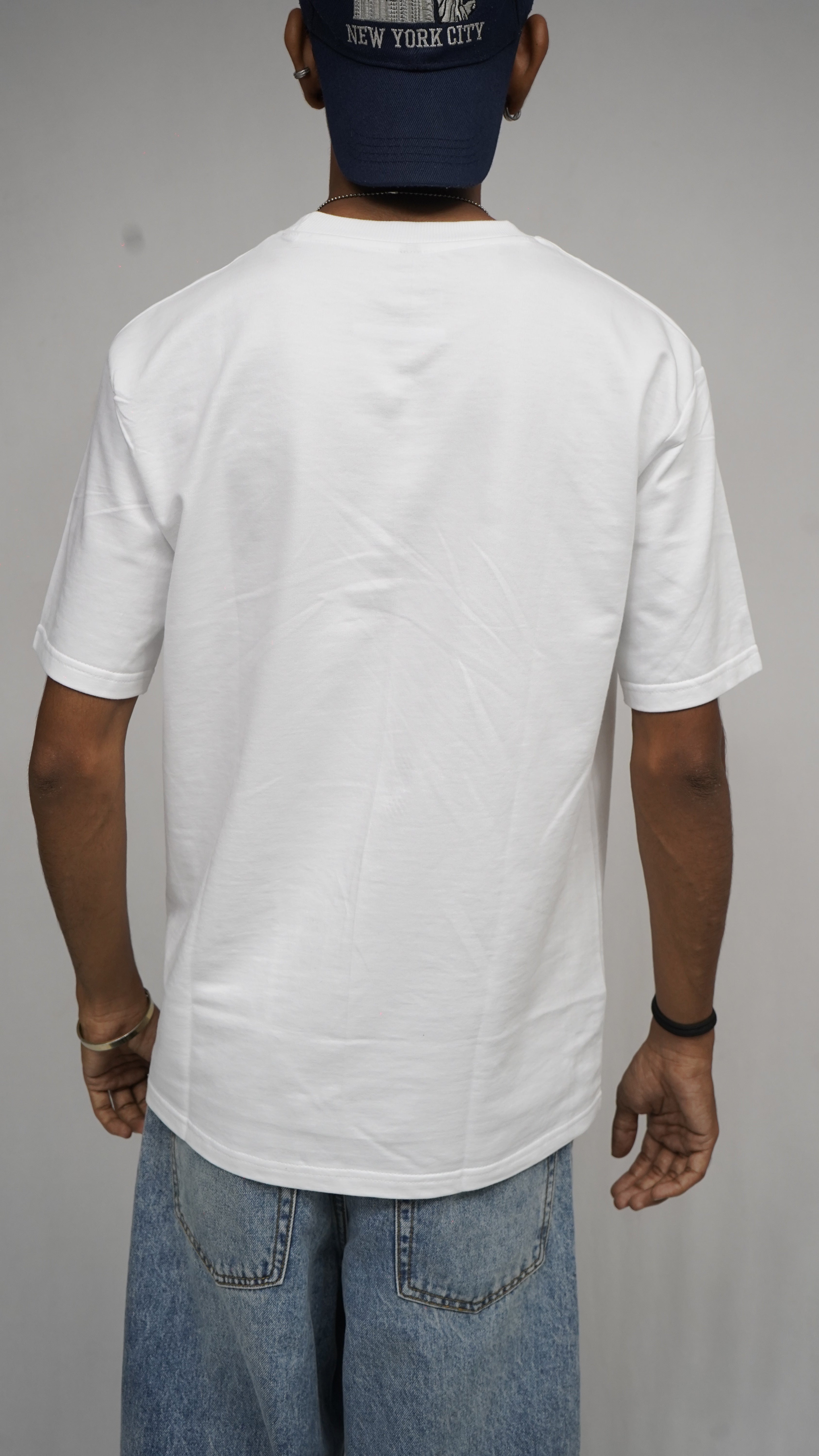 Person wearing a white shirt and blue jeans on a plain background