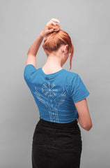 Person wearing a blue t-shirt with a design on the back, standing against a gray background