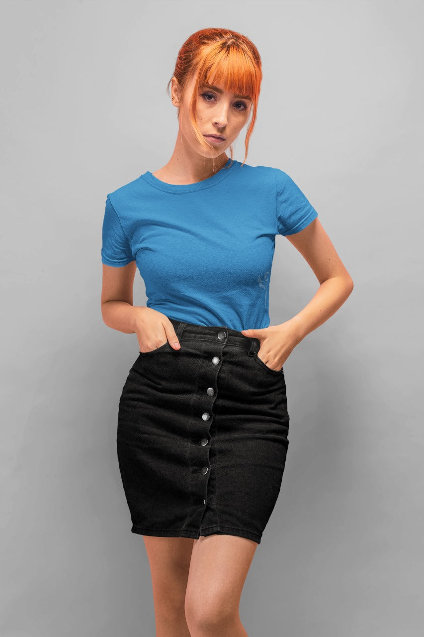 Woman wearing a blue t-shirt and black skirt against a gray background