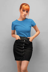 Woman wearing a blue t-shirt and black skirt against a gray background