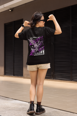 Person wearing a black t-shirt with a graphic design, standing in front of a building.