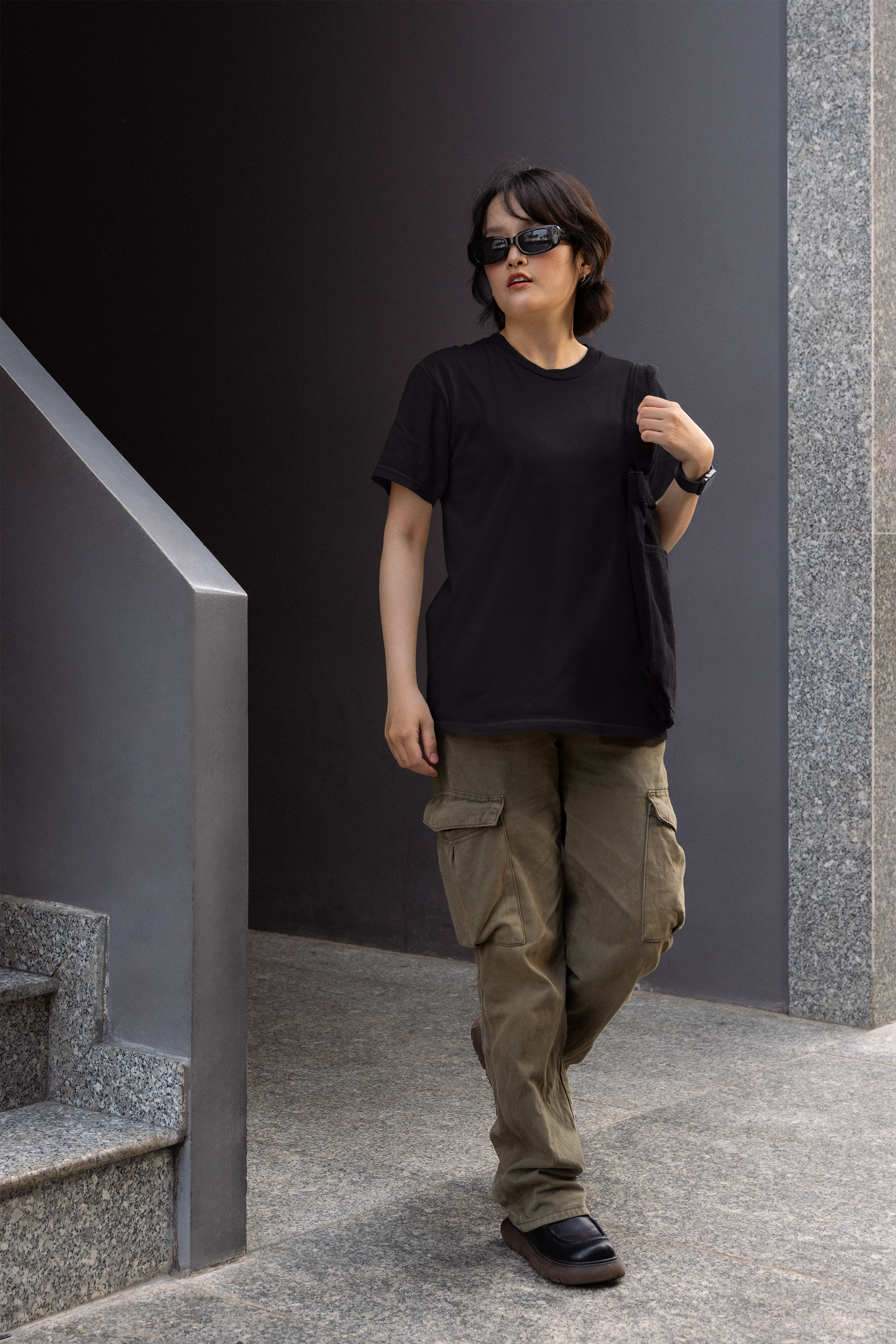Person wearing a black t-shirt and brown cargo pants standing on a staircase.