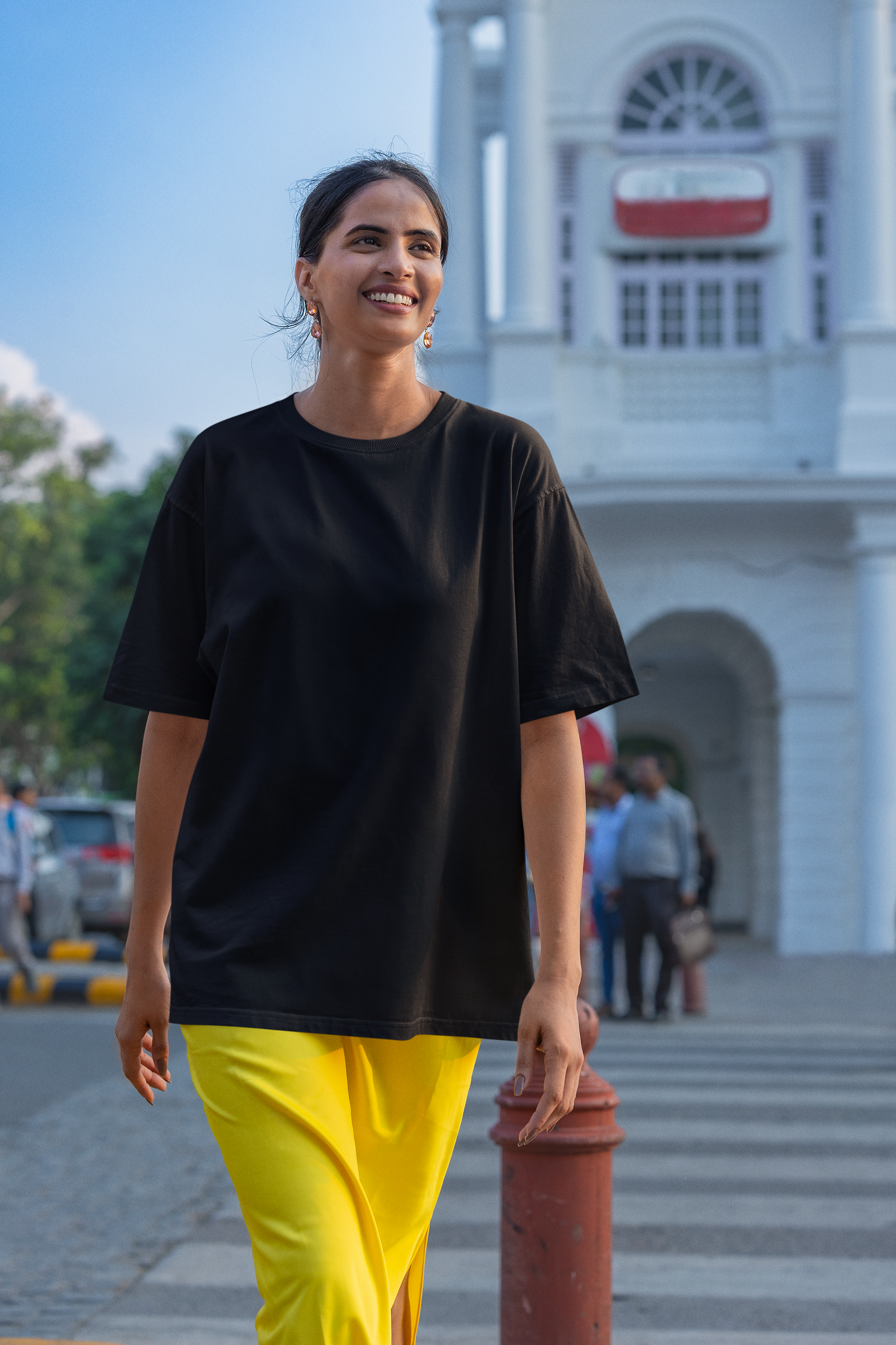 Woman in black top and yellow pants walking in an urban setting