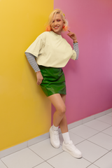 Person wearing a yellow sweater, green skirt, and white sneakers against a pink and yellow wall Oversized T-Shirt From Kapda Kulture.