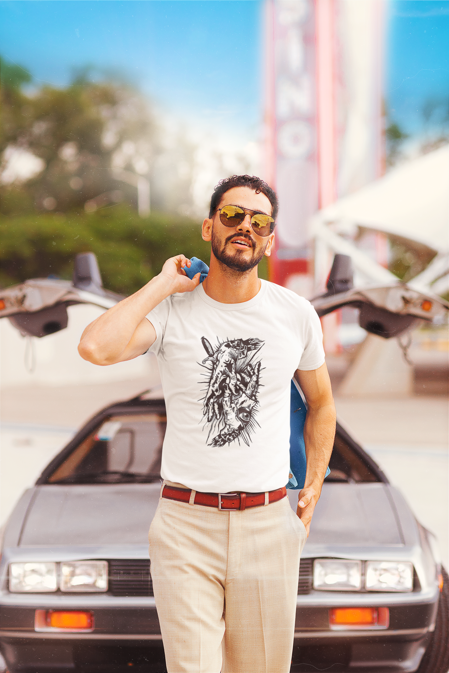 Man standing in front of a vintage car wearing a white t-shirt with a graphic design Slim Fit T-Shirt From Kapda Kulture.