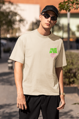 Person wearing a beige t-shirt with green text, black cap, and sunglasses outdoors  Oversized T-Shirt From Kapda Kulture.
