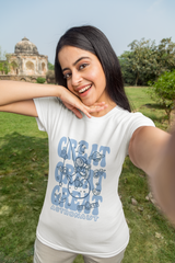 Woman wearing a white t-shirt with blue text and graphics, standing outdoors.