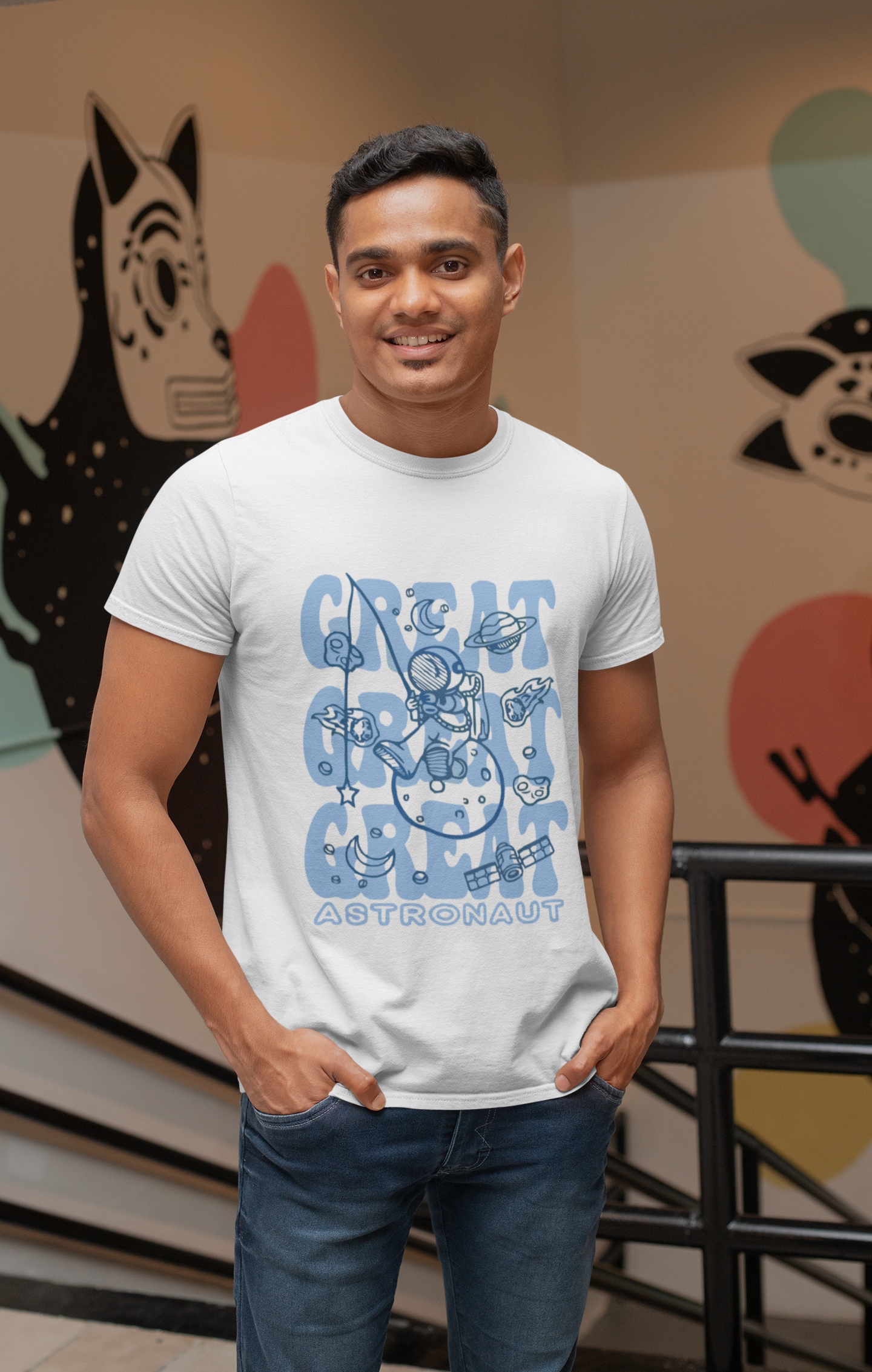 Man wearing a white t-shirt with blue graphic design in front of a colorful wall.